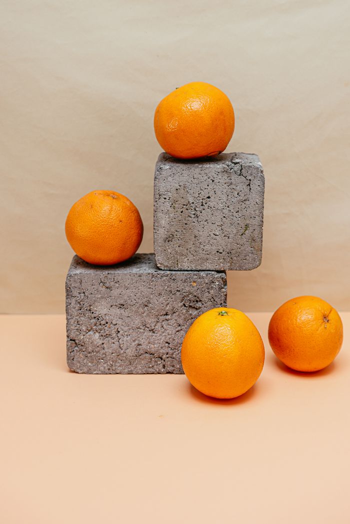 Fresh oranges artistically arranged on textured concrete blocks in a minimalist still life.